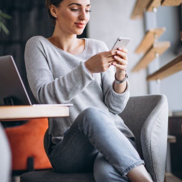 Mujer sentada en un café tomando café y trabajando en una computadora _ Foto Gratis